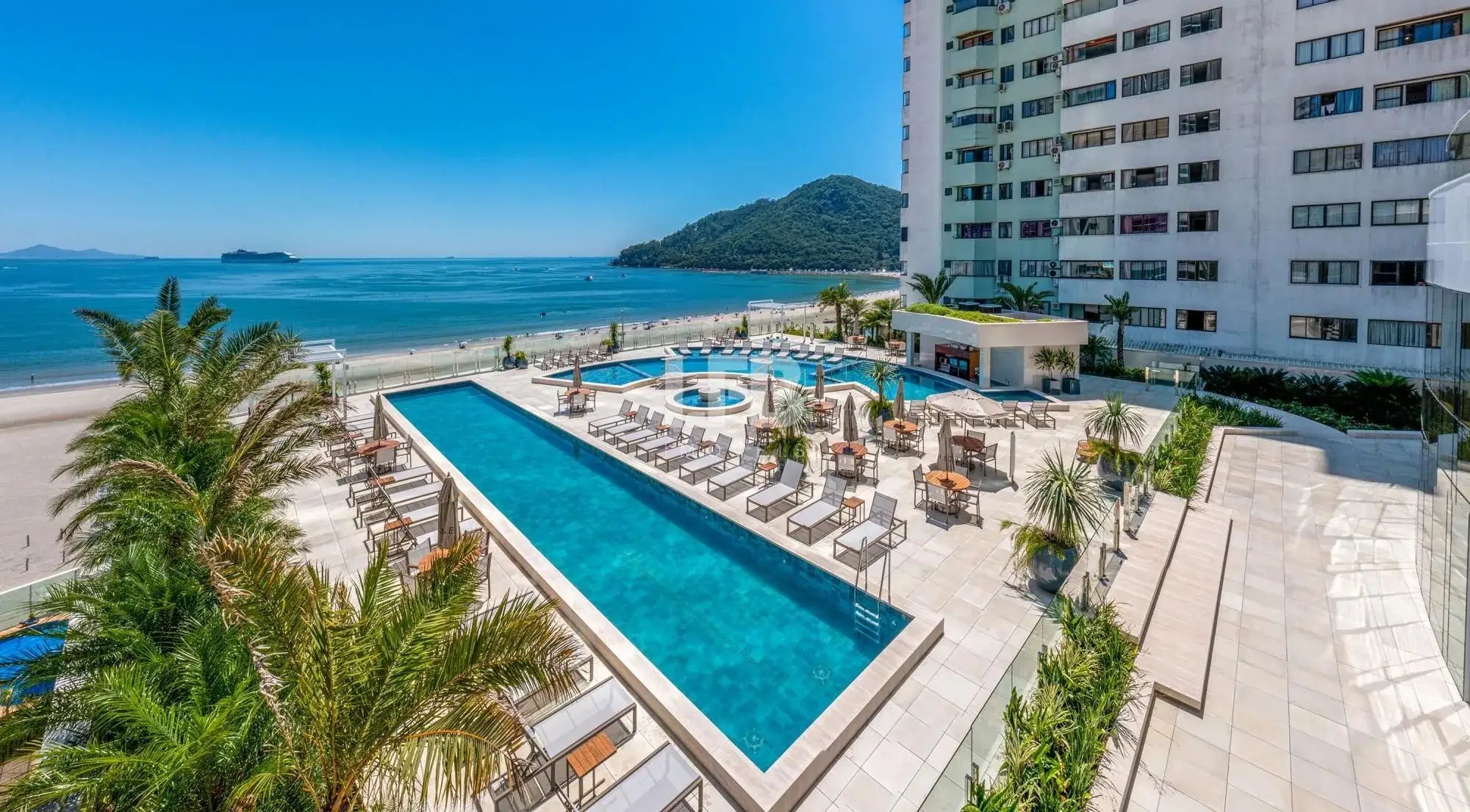 Piscina do One Tower com espreguiçadeiras e vista para o mar de Balneário Camboriú